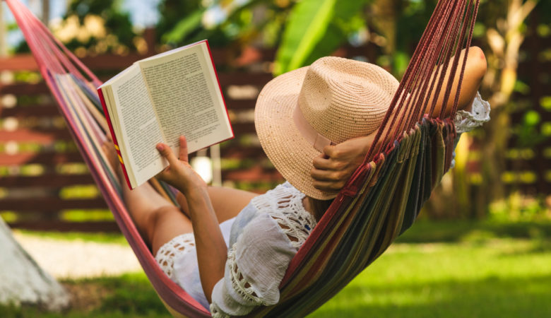 Happy beautiful woman in white dress relaxing in hammock.